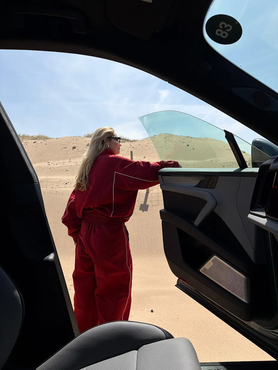 Woman in desert landscape leaning on door of car