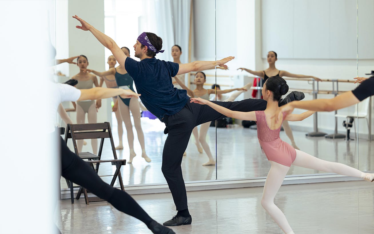 Ballet teacher showing dancers moves in front of mirror