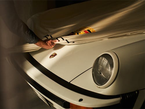 White 1983 911 being tucked under a Porsche car cover