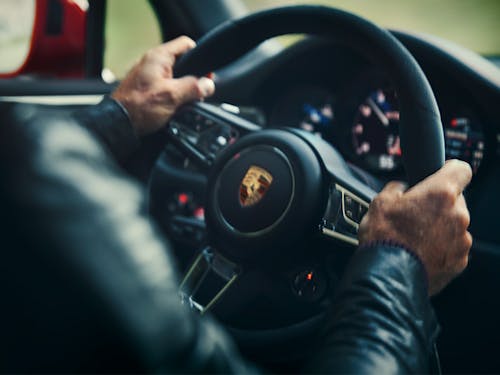 Man driving a Porsche, close-up of hands on steering wheel
