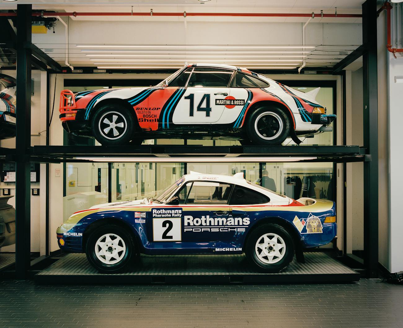 Porsche racecars in racing livery in the Porsche Museum workshop