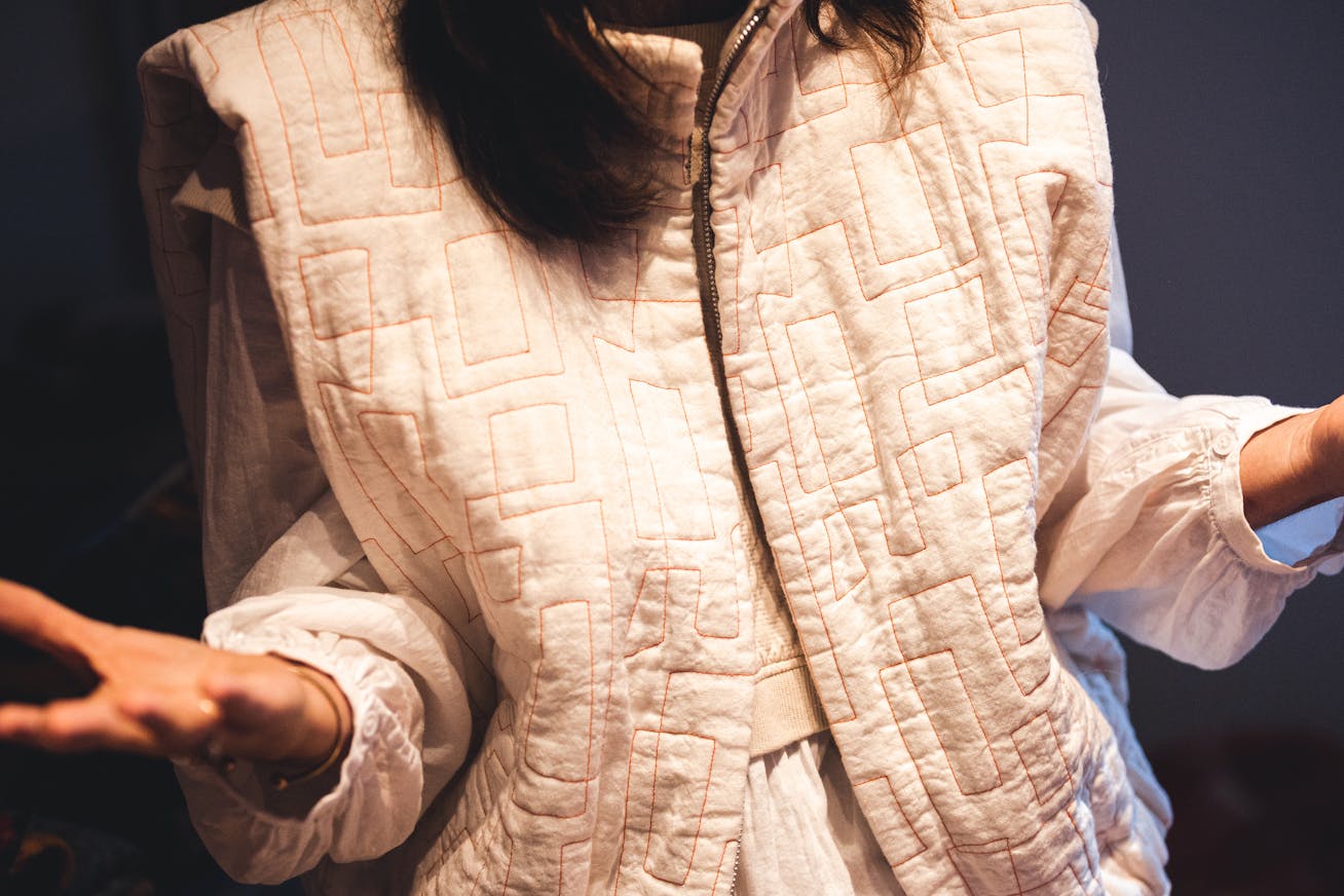 Woman wearing gilet-style jacket, hands outstretched