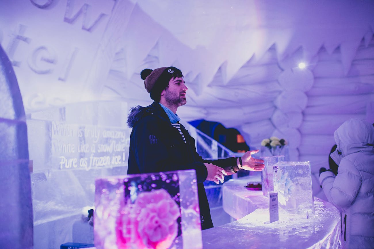 Man behind ice bar in middle of snow hotel igloo