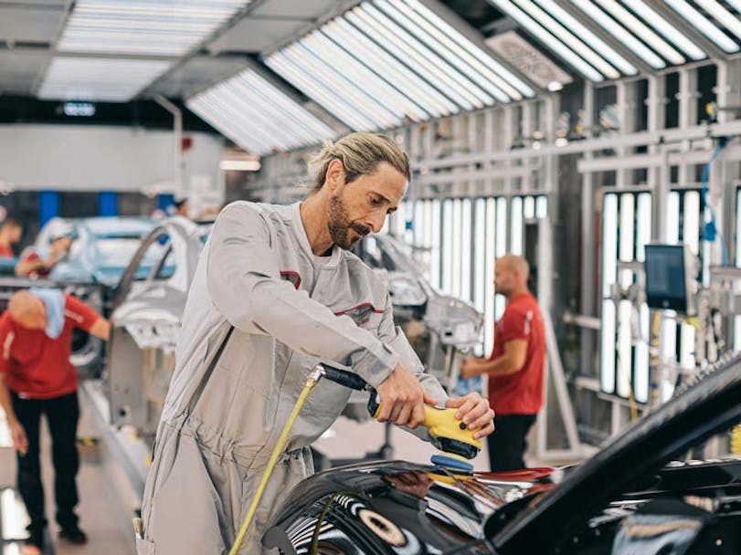 Adrien Brody working on Porsche car in factory