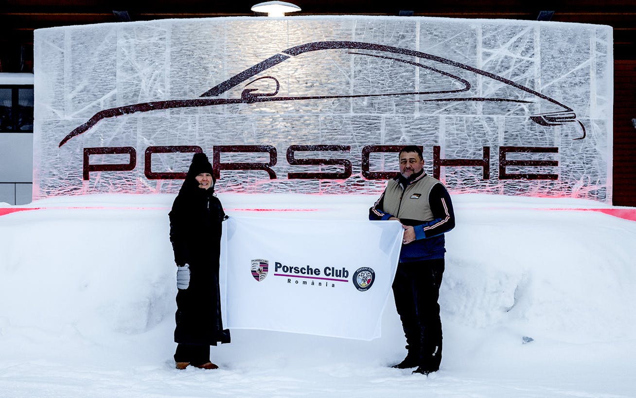 Man and woman hold up Porsche Club Romania banner