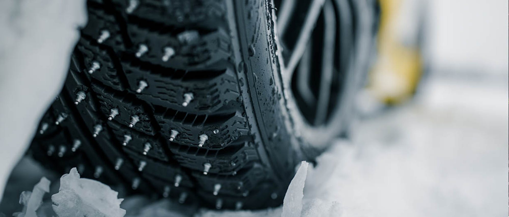 Detail of a car tire in the snow with spikes