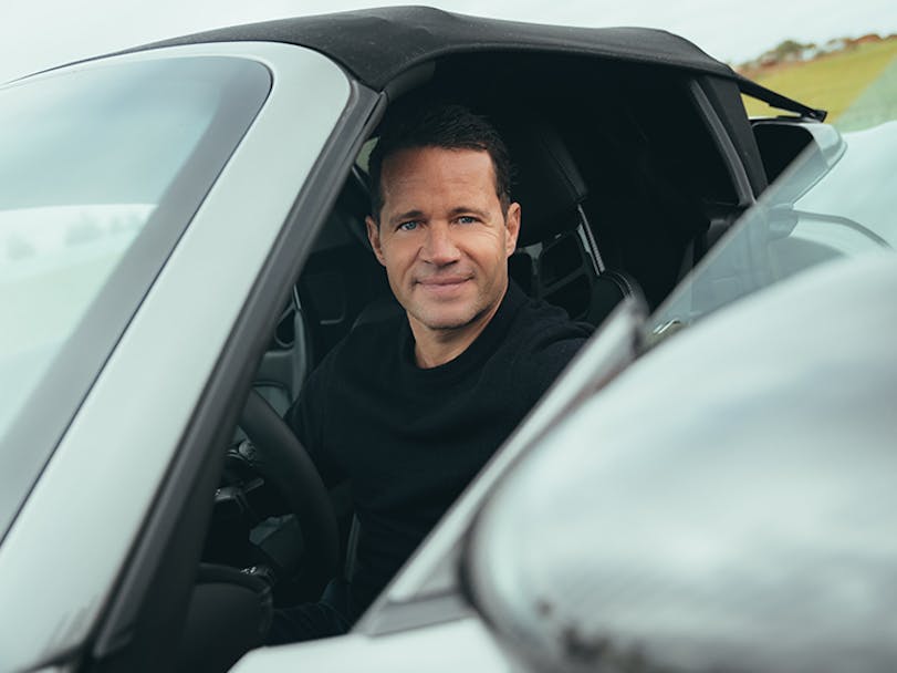 Smiling man sitting inside Porsche 718 Spyder RS