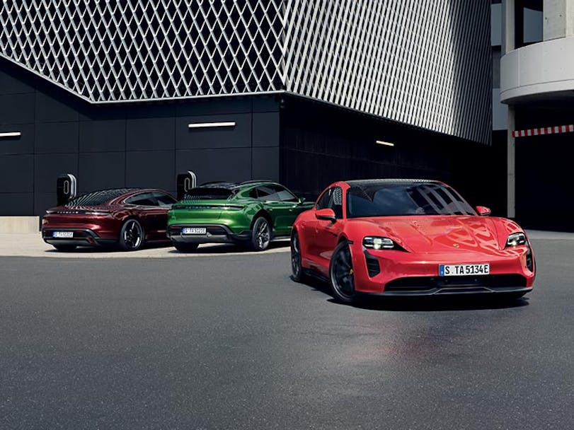 Three Porsche Taycan models parked next to modern building