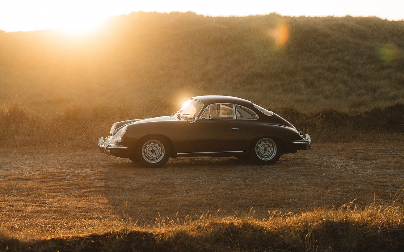 Classic black Porsche 356 parked at sunset on dirt track