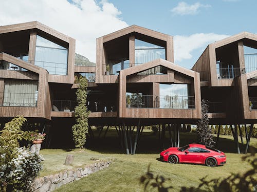 Red Porsche 911 parked in a meadow in modern wooden buildings