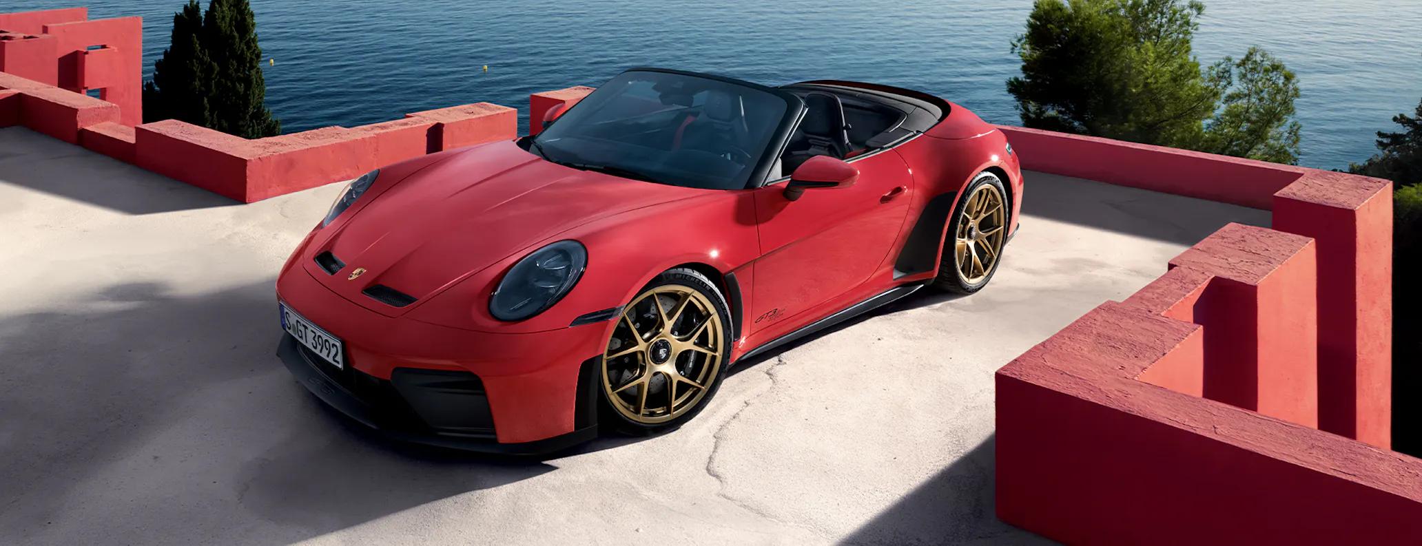 Porsche 911 GT3 S/C in Guards Red parked on roof by ocean three quarter view hero desktop