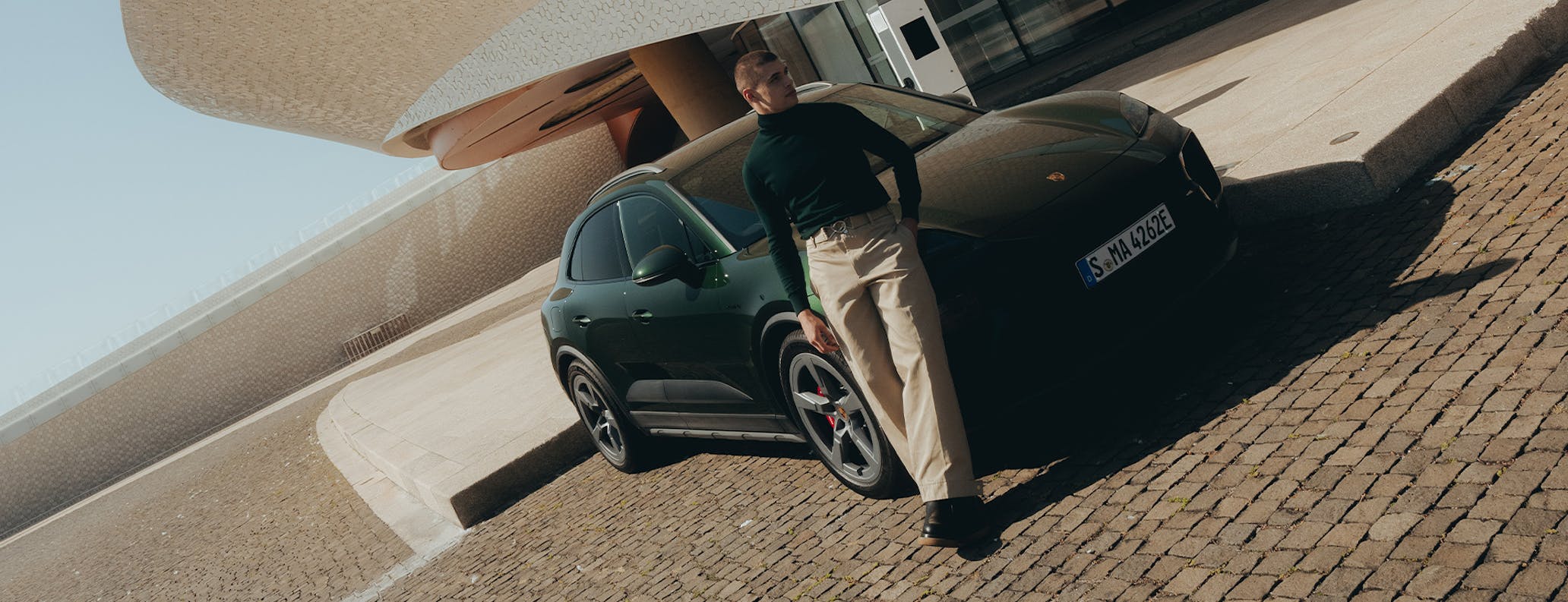 Man leaning on green Porsche Macan Electric