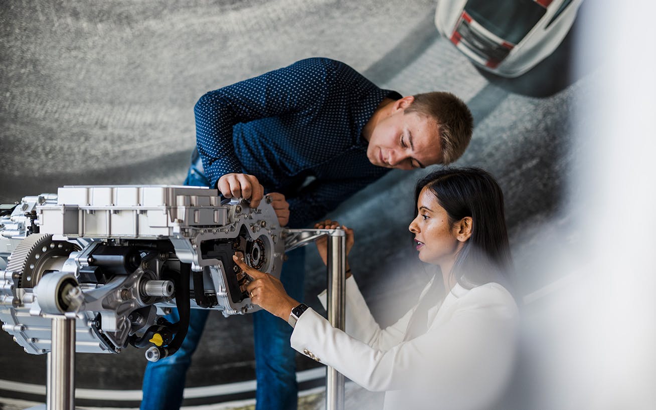 Woman and man inspect the electric drivetrain of a Porsche