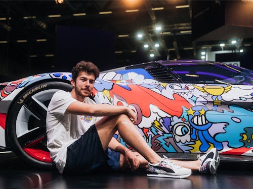 Artist Vexx sitting next to Porsche painted with colourful cartoons