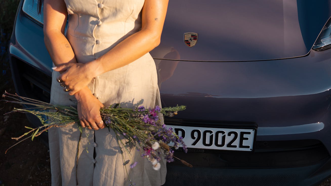 Close-up of person holding lavender, Porsche Macan behind