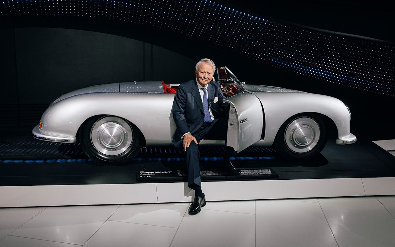 Man sitting in Porsche 356 on display at Porsche Museum