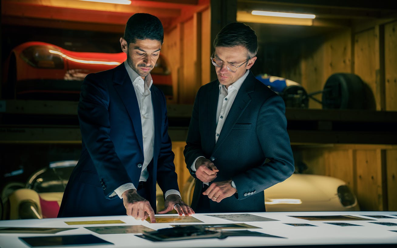 Two men look over Porsche documents on lightbox