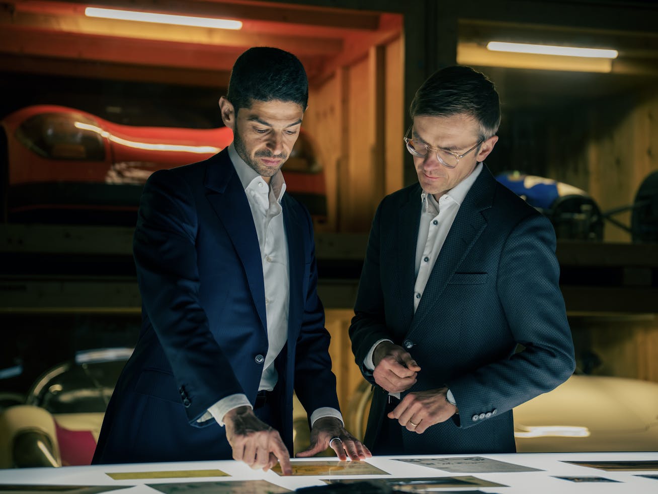 Two men look over Porsche documents on lightbox