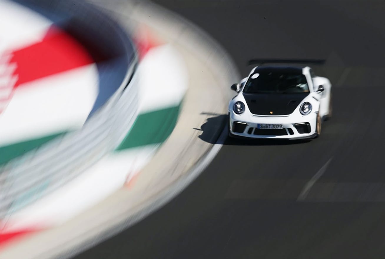 White Porsche 911 GT3 RS driving through bend on racetrack