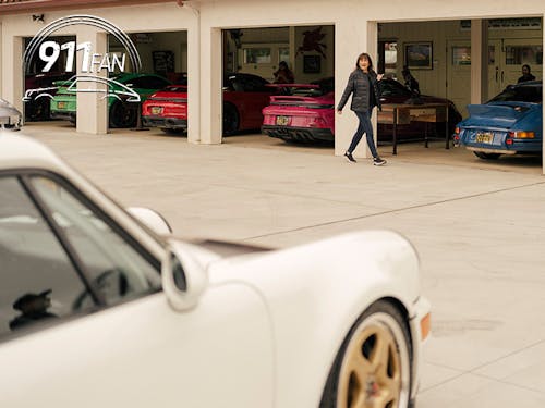 Woman walks past garage doors revealing several Porsche 911 sportscars