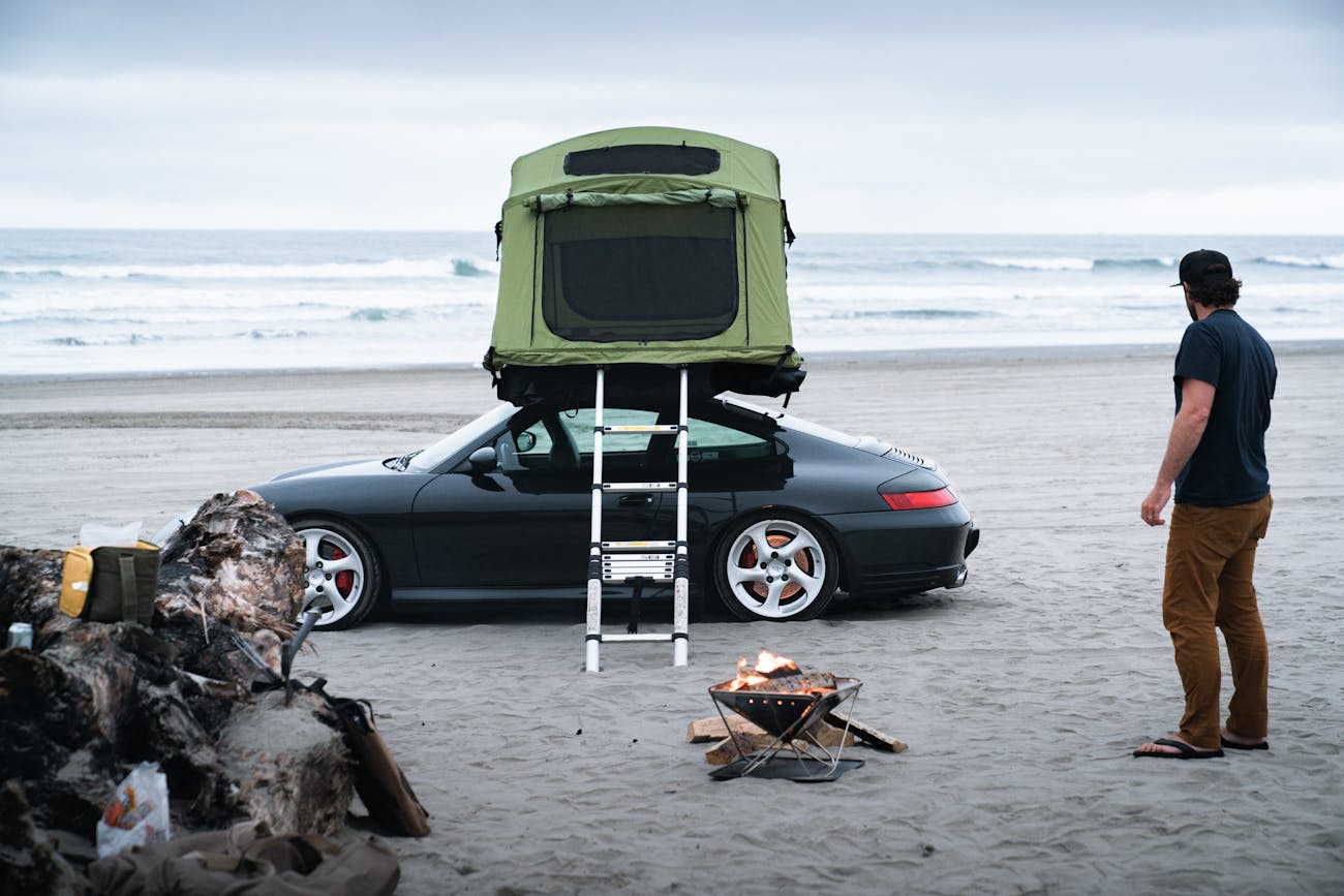 Porsche parked on beach with a tent on the roof
