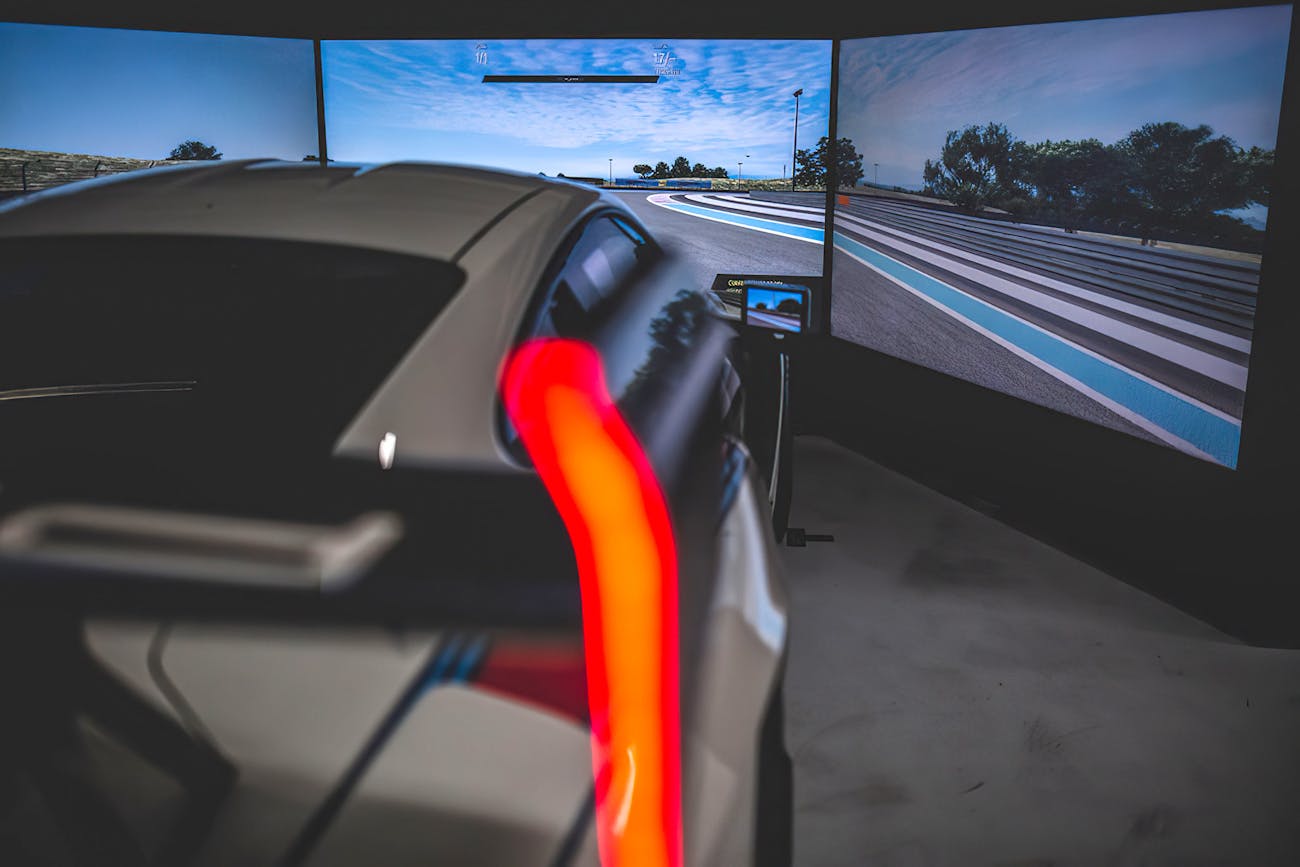 Person holds steering wheel of a Porsche simulator