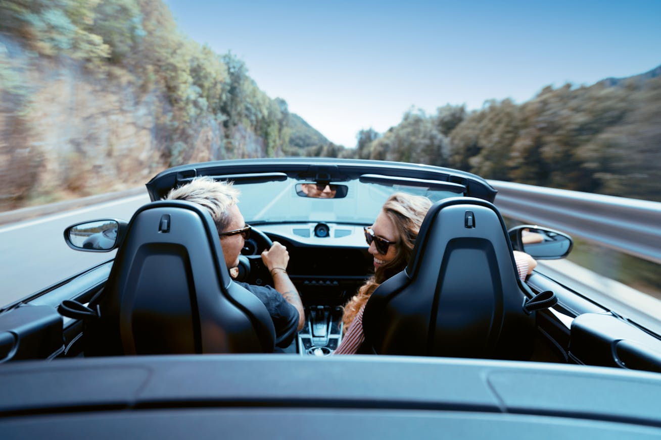 Porsche Travel Experience of man and a woman driving a Porsche 911 Cabriolet, roof down