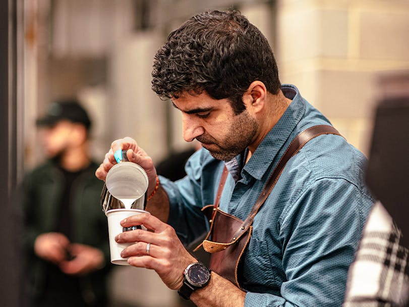 Barista pouring a cup of coffee in coffee shop