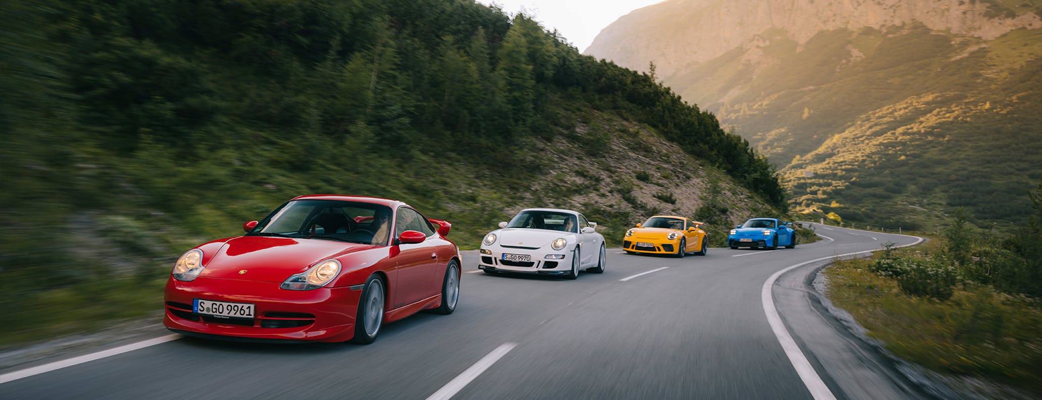 Four generations of Porsche 911 GT3 on mountain road