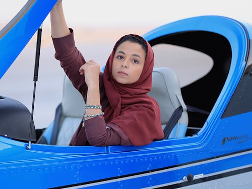 Woman in hijab sat in light aircraft, lifting its canopy