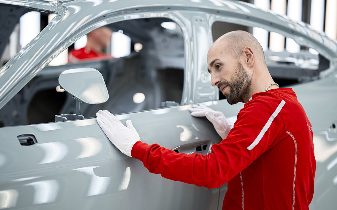 Man inspects Porsche Taycan at Porsche factory in Zuffenhausen, Germany