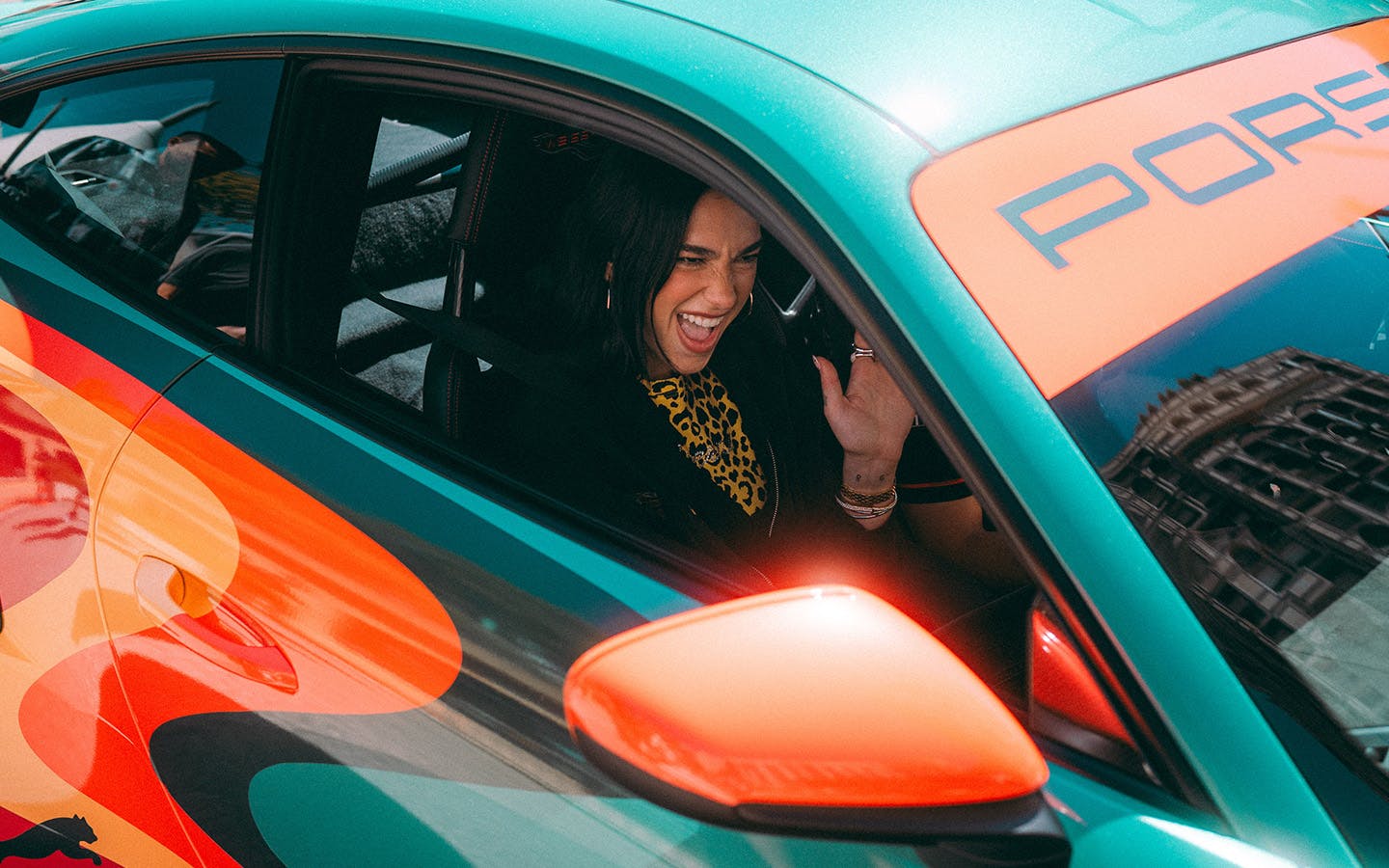 Dua Lipa waving from Dua Lipa Rennstall GT3 RS sportscar