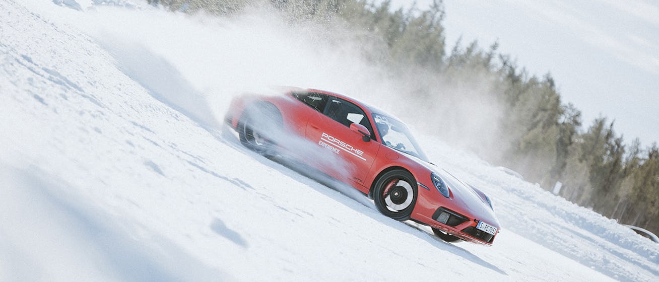 Red Porsche 911 kicking up snow at Porsche Ice Experience