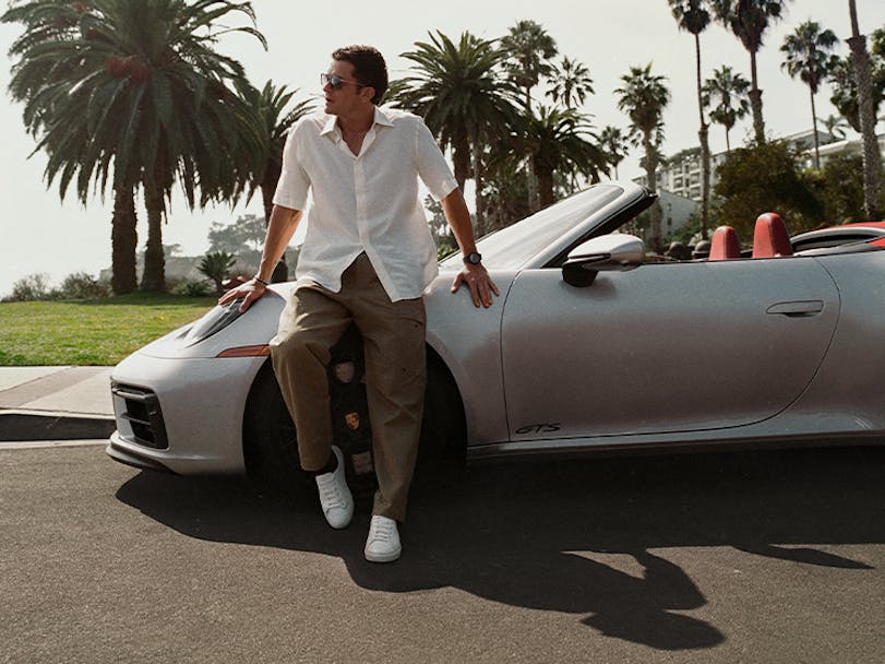 Orlando Bloom leaning against Porsche 911 Carrera GTS Cabriolet