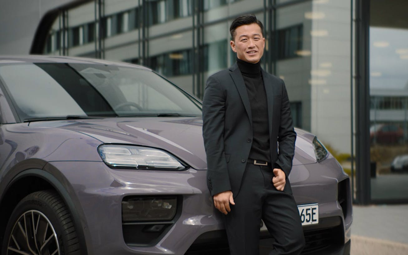Man wearing a suit standing in front of Porsche Macan