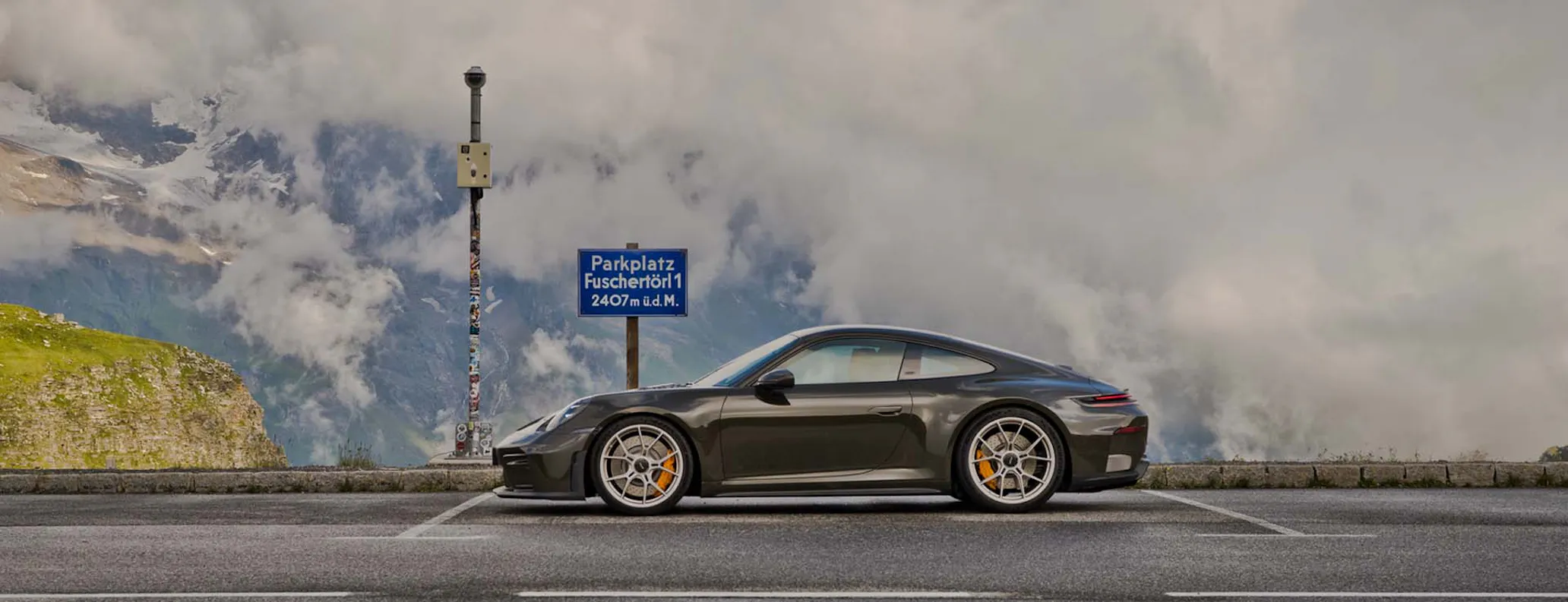 Porsche GT3 Bergsport parked on mountain road with clouds in background