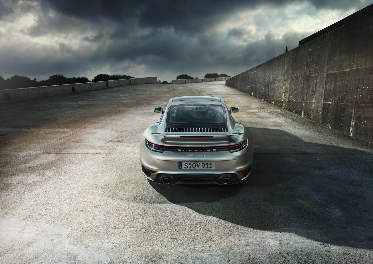 Rear view of Porsche 911 Turbo S (992.1) parked beside concrete wall