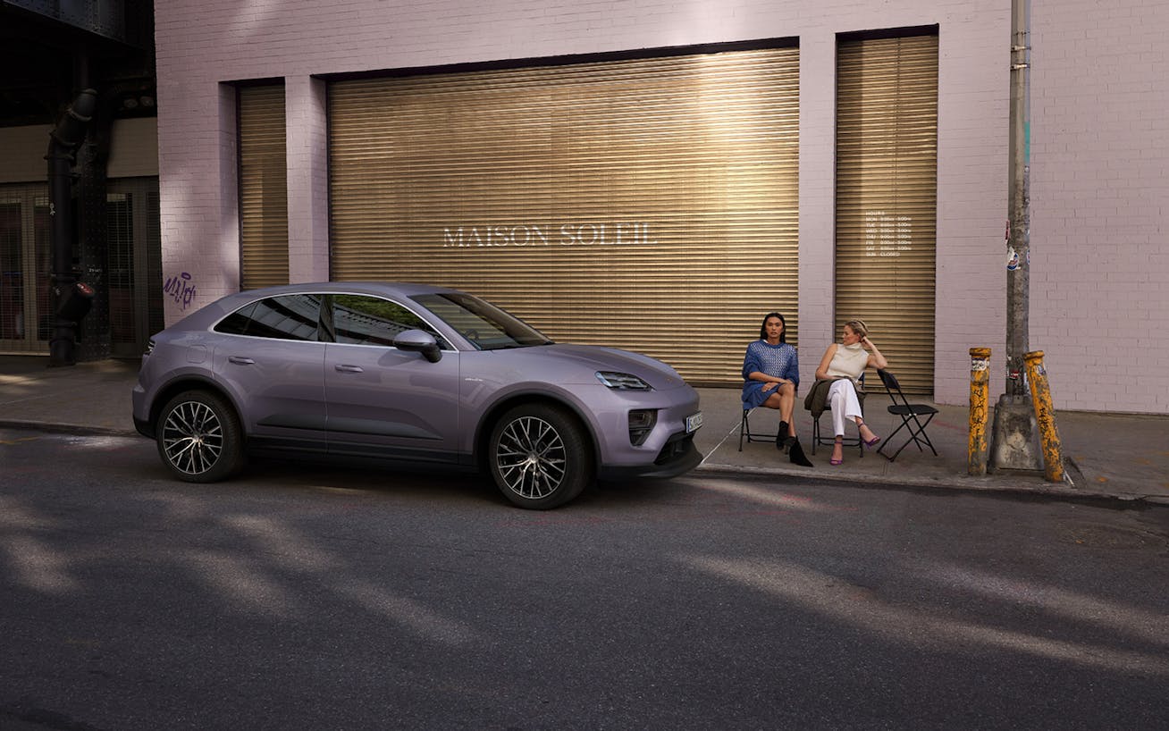 Two women sitting beside new Porsche Macan 4 Electric