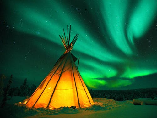 Teepee lit up in snow, Northern Lights in sky