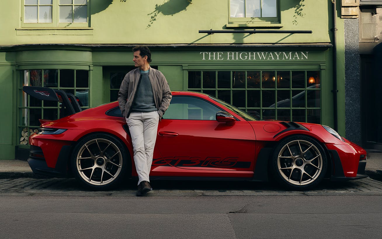 Mark Webber leaning on red Porsche 911 GT3 RS