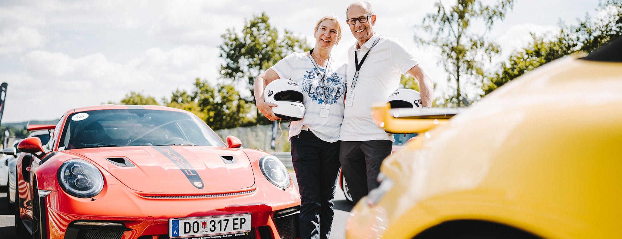 Couple stand in front of red Porsche 911 GT3 at the Porsche Track Experience at the Nürburgring [credits Photo: Porsche]