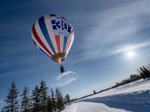 A hot air balloon flies over a snowy Finnish landscape