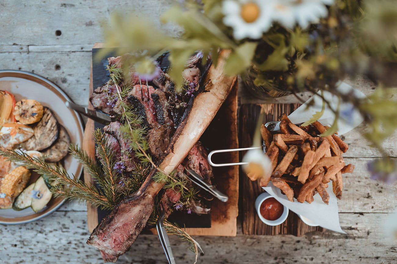 Grilled meat with alpine spruce needles, grilled vegetables and chips