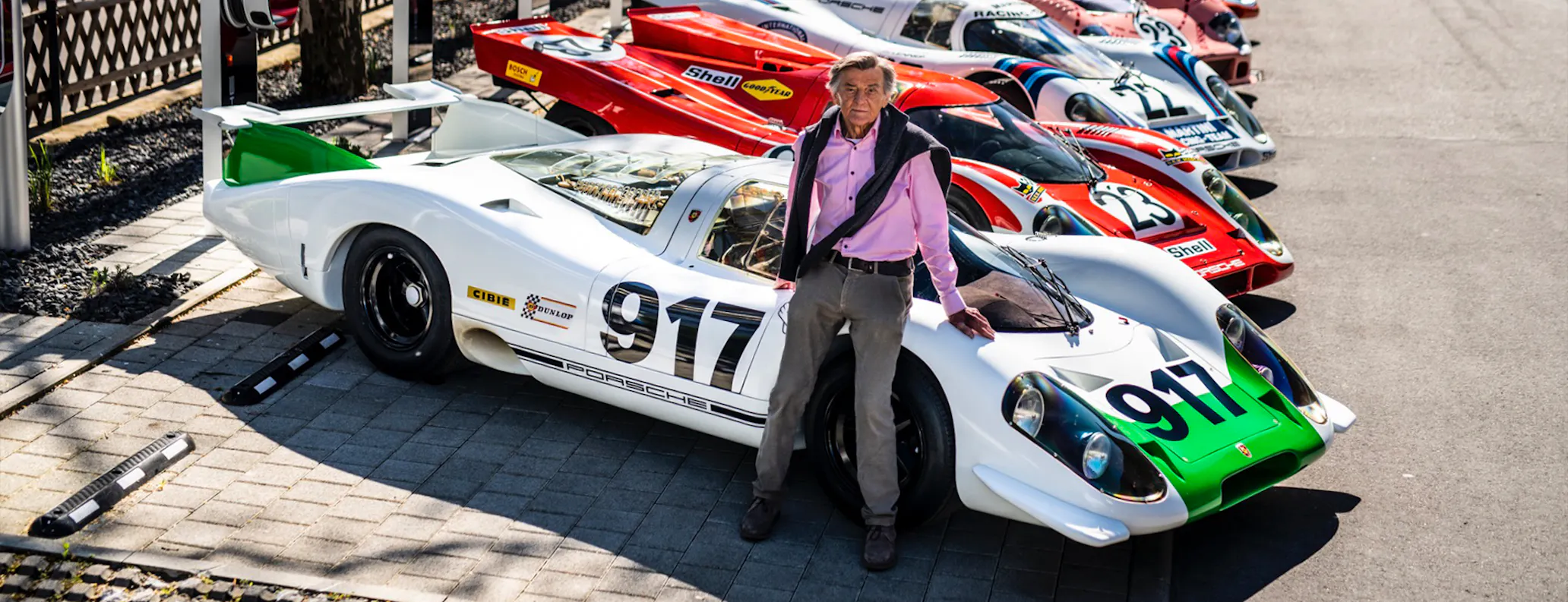 Famous German engineer Hans Mezger leaning on a Porsche 917 race car 