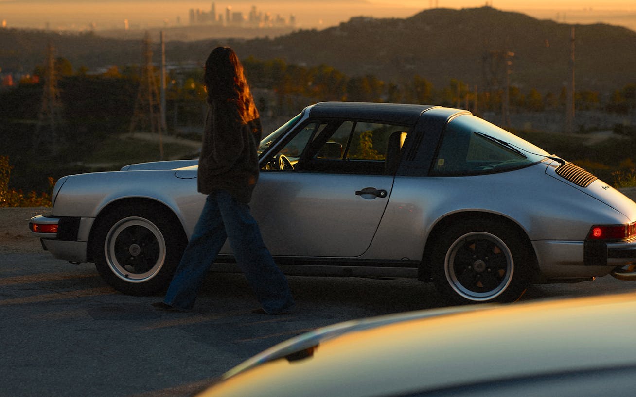 Julie Sariñana, aka Sincerely Jules, with classic Porsche 911 Targa at dusk, downtown LA in distance