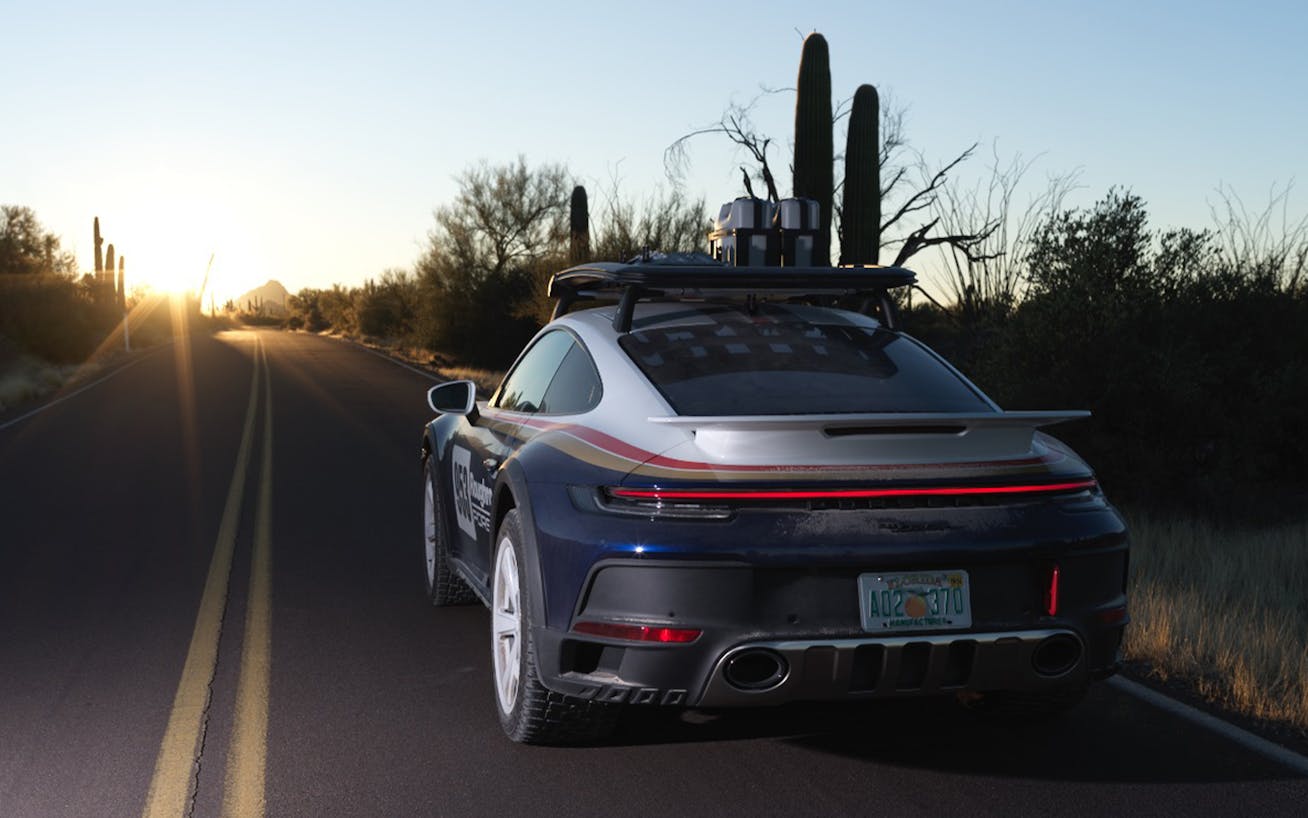 Rear view of Porsche 911 Dakar driving on road at dusk