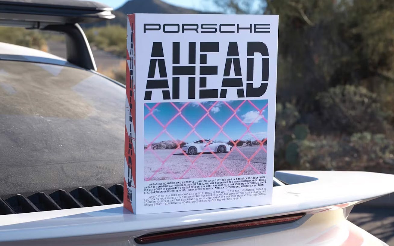 Porsche AHEAD coffee table book propped up on car wing 