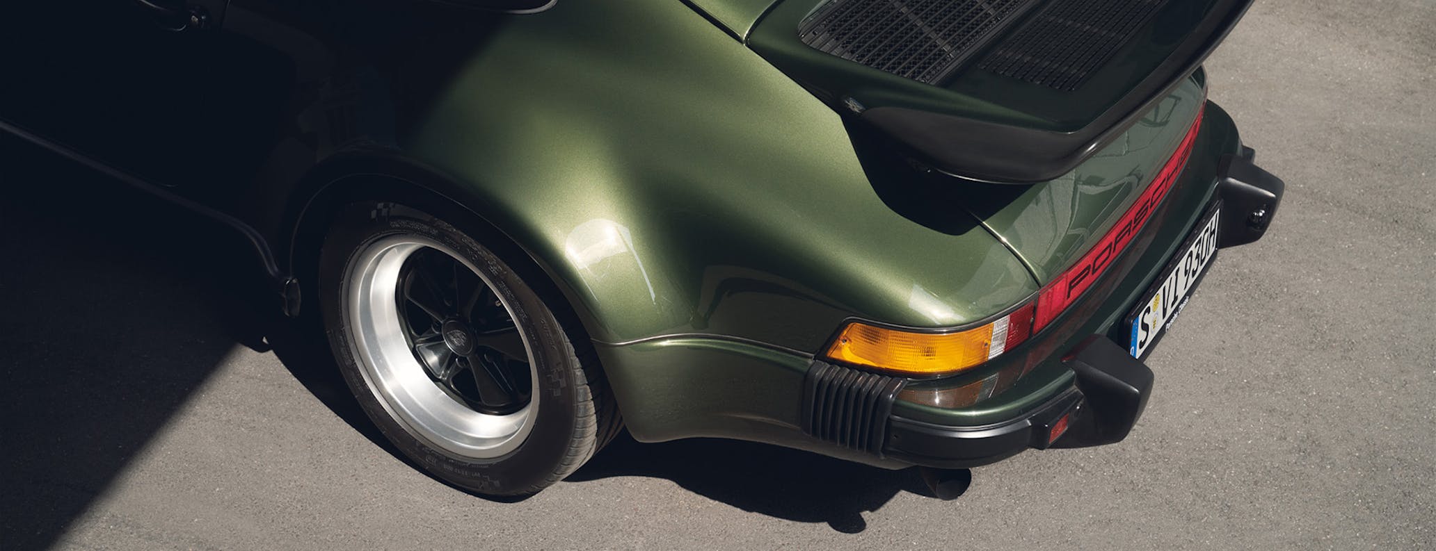 Green Porsche 911 G series in parking lot 