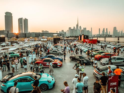 Porsche cars lined up at event, Dubai evening skyline behind