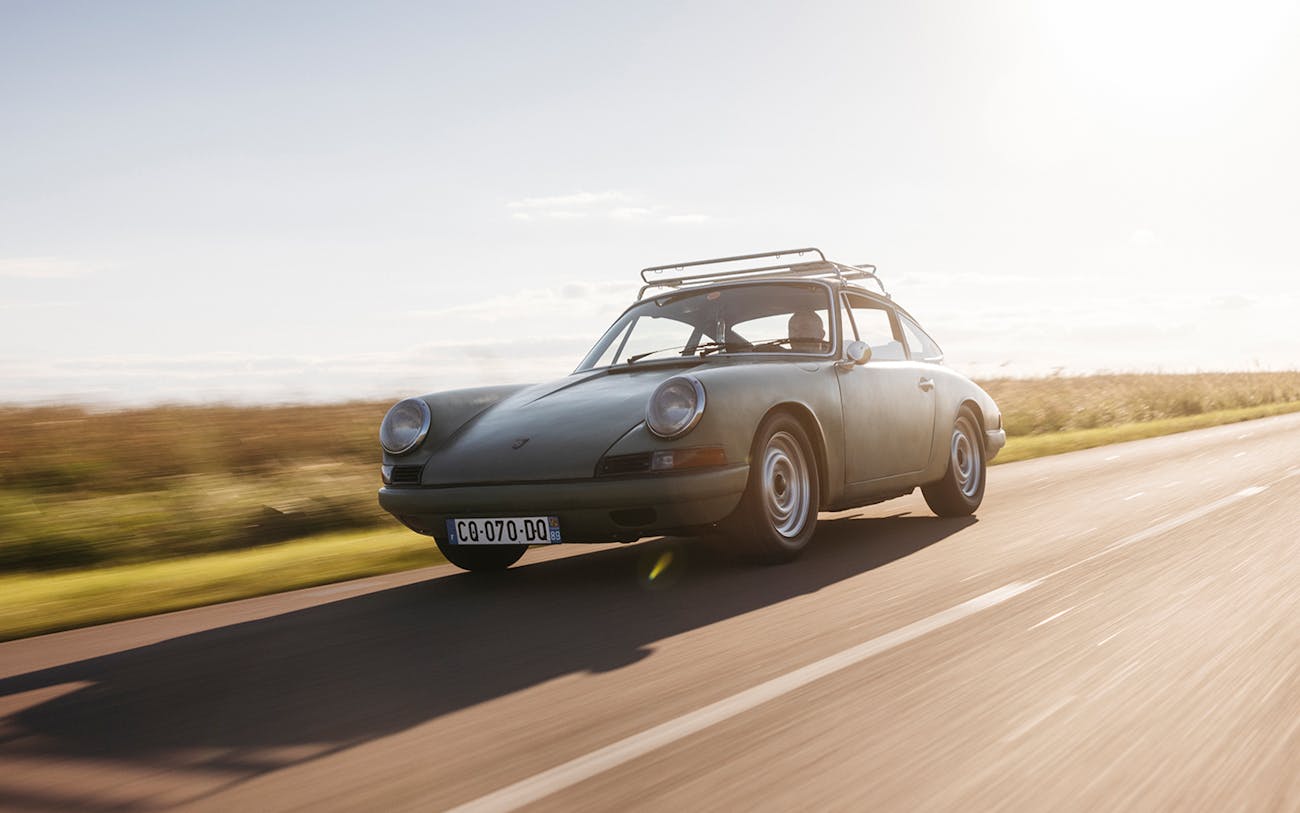 Green Porsche 912 driving on country road during sunset